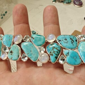 Elurõõmu käekett Kolmerealine suuremate erikujuliste türkiiside, ovaalsete kuukivide ja tilgakujuliste helesiniste topaasidega T-lukuga võimas käekett