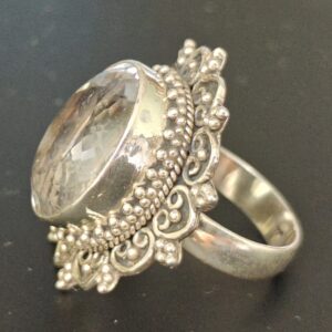 suure ovaalse mäekristallga hõbesõrmus. Kivi ümbristeb nikerdustega raam