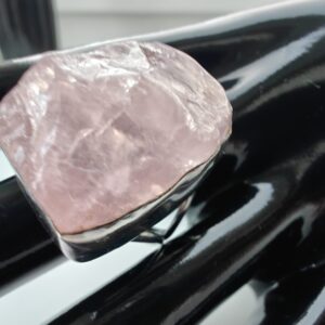 Suure pooltöödeödud roosa kvartsiga sõrmus mustal plastikkäel