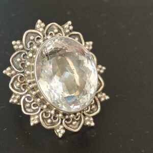 suure ovaalse mäekristallga hõbesõrmus. Kivi ümbristeb nikerdustega raam