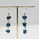 Kolme pooltöödeldud toorkiviga, erksinise apatiidiga ketina alla rippuvad konksuga hõbekõrvarõngad