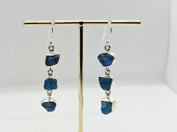 Kolme pooltöödeldud toorkiviga, erksinise apatiidiga ketina alla rippuvad konksuga hõbekõrvarõngad